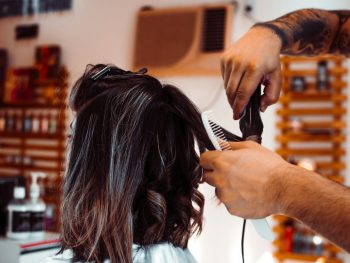 woman in white shirt holding hair blower