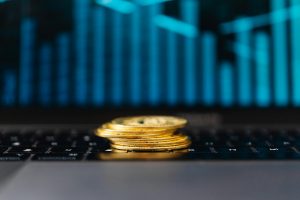stack of gold coins on a laptop displaying a graph