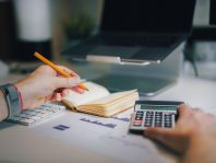 a person sitting at a desk with a calculator and a notebook