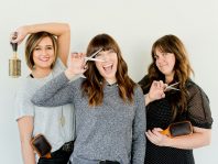 three women holding scissors and brush