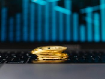 stack of gold coins on a laptop displaying a graph